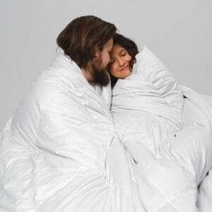 A boy and girl wrapped in a luxurious eiderdown duvet, made with 100% Icelandic eider duck down for exceptional comfort and warmth.