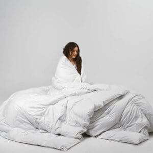 A girl wrapped in a luxurious eiderdown duvet, made with 100% Icelandic eider duck down for unmatched comfort and warmth.